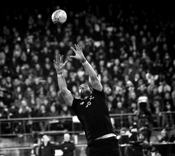 Rugby player rising to catch a lineout ball in front of a packed stand