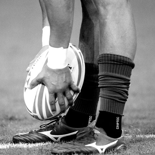 Rugby player's hand pressing the ball into the turf before a place kick